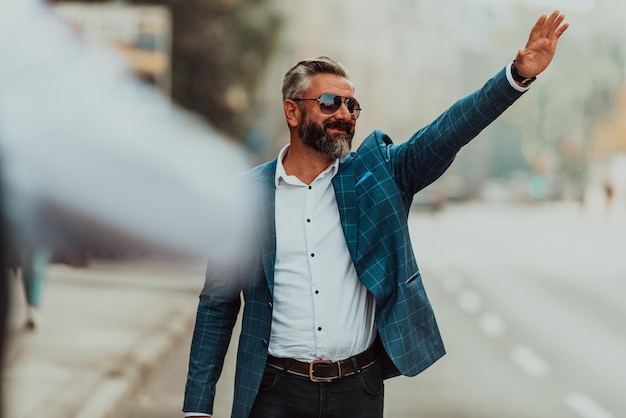 Modern senior businessman stopping a taxi in the city.