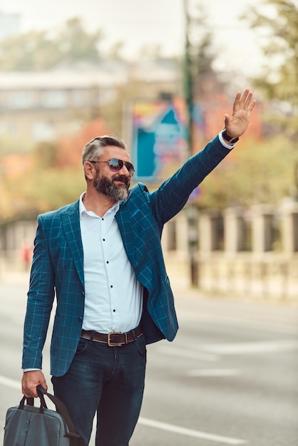 Modern senior businessman stopping a taxi in the city.