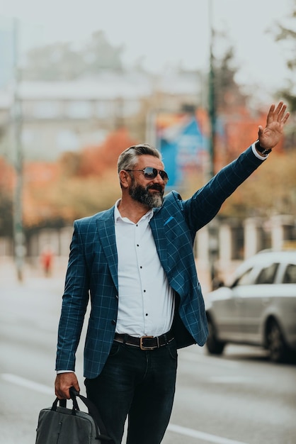 Modern senior businessman stopping a taxi in the city.