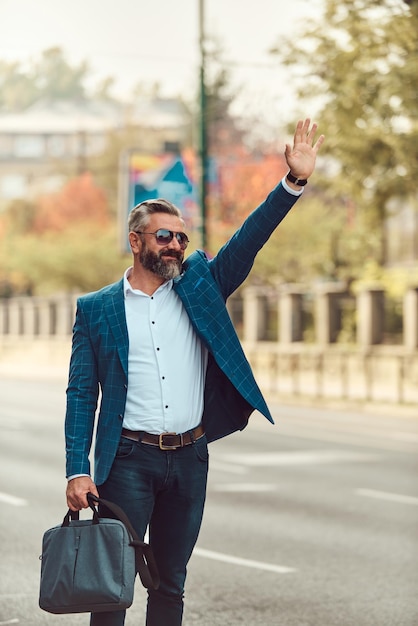 Modern senior businessman stopping a taxi in the city.