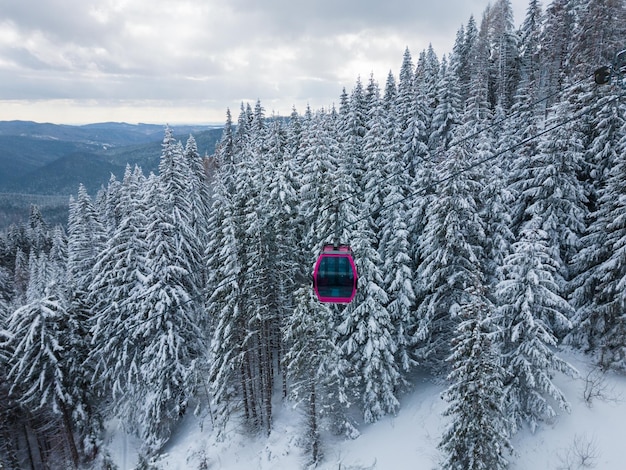 Modern ski lift gondola against snowcovered fir forest and mountains