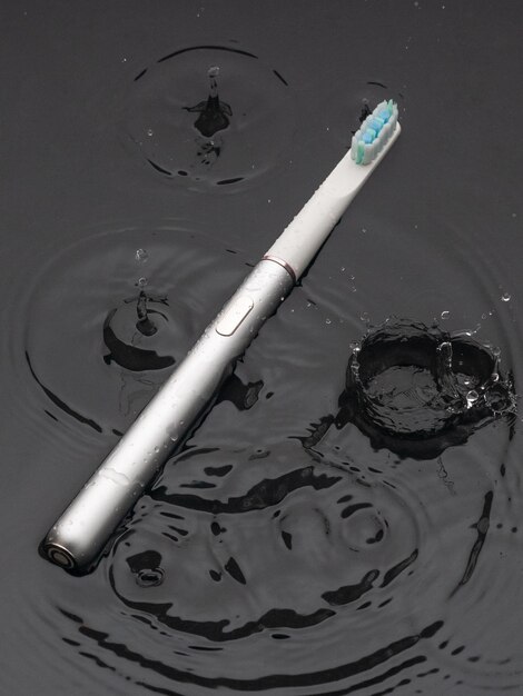 Modern sonic electric toothbrushes Made from gray metal Professional oral care and healthy teeth Minimalistic design They lie in the water Black background