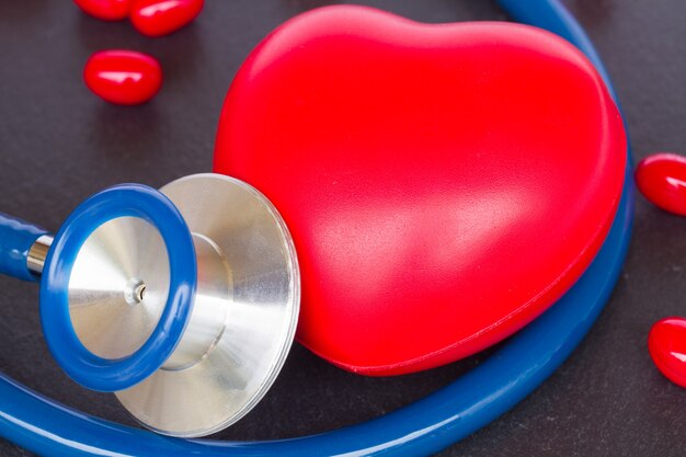 Modern stethoscope with red heart close up