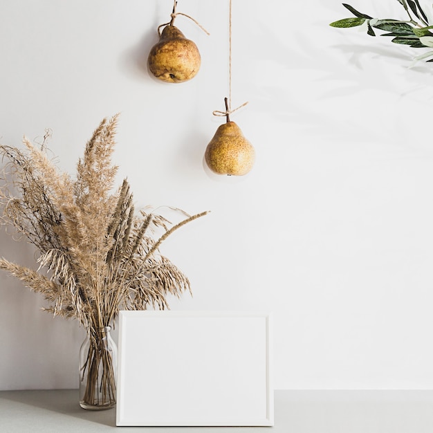 Modern still life with white blank photo frame, pampas grass and pears