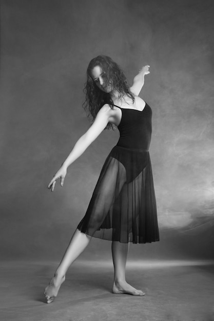 Modern style dancer posing on a studio grey background in fog