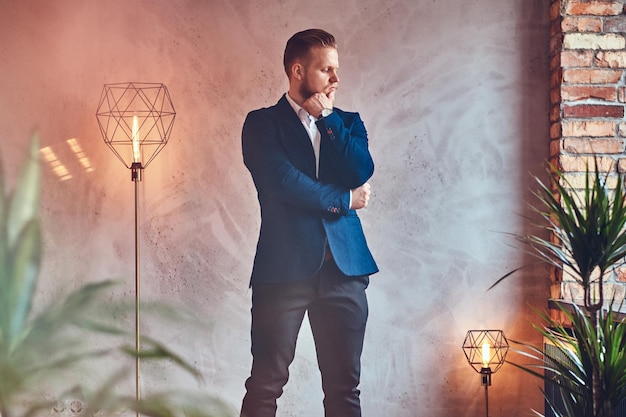 A modern, stylish male dressed in an elegant suit posing in a room with loft interior.