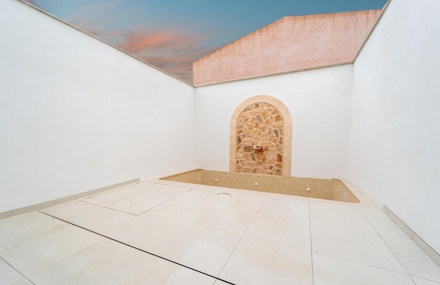 Modern swimming pool terrace with a stone made fountain and an empty swimming pool