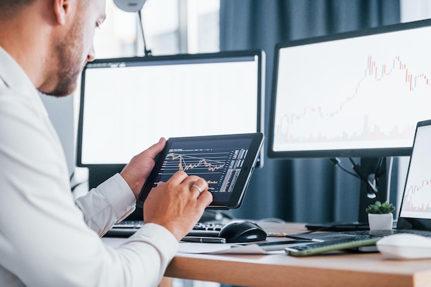 Modern technologies Young businessman in formal clothes is in office with multiple screens