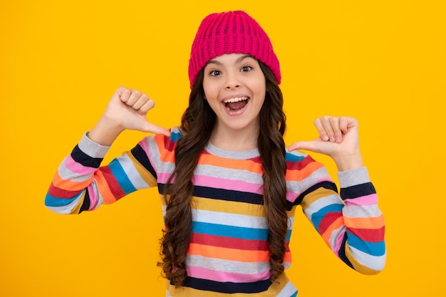 Modern teenage girl 12 13 14 year old wearing sweater and knitted hat on isolated yellow background Happy teenager positive and smiling emotions of teen girl