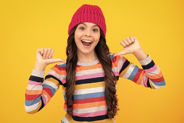 Modern teenage girl 12 13 14 year old wearing sweater and knitted hat on isolated yellow background Happy teenager positive and smiling emotions of teen girl