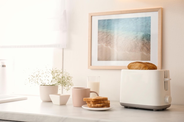 Modern toaster flowers and tasty breakfast on counter in kitchen