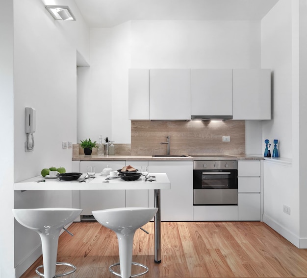 Modern total white kitchen interior with wooden floor in the foreground two stools