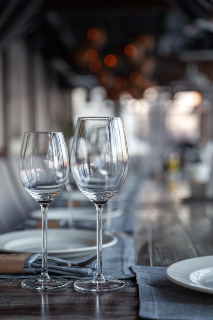 Modern veranda restaurant interior, banquet serving, wine and water glasses, plates, forks and knives, textile napkins. Concept banquet, birthday, conference, group lunch, vertical, copy space