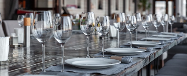 Modern veranda restaurant interior, banquet setting, glasses, plates