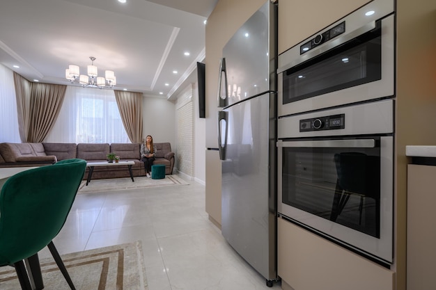 Modern white and beige large kitchen with dining table and sofa in studio apartment