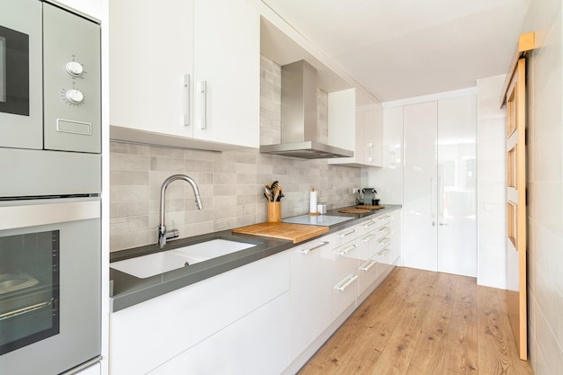 Modern white kitchen with wood flooring. Cabinet handles with a soft sponge to protect a child