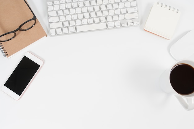 Modern white office desk table with laptop computer, smartphone with black screen mobile.