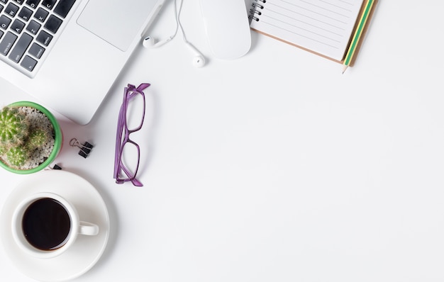 Modern white office desk table with laptop, mouse and other supplies with cup of coffee. Blank noteb