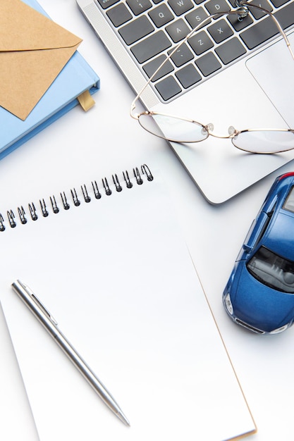 Modern white office desk table with laptop notebook toy car and other supplies