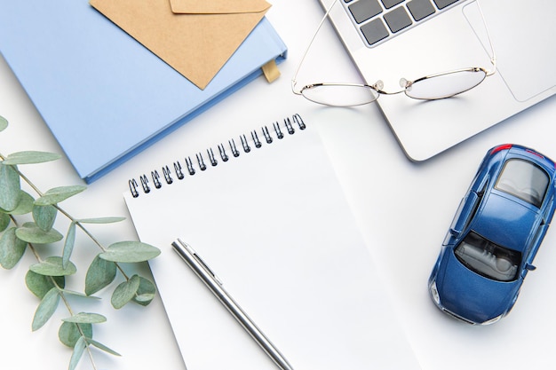 Modern white office desk table with laptop notebook toy car and other supplies