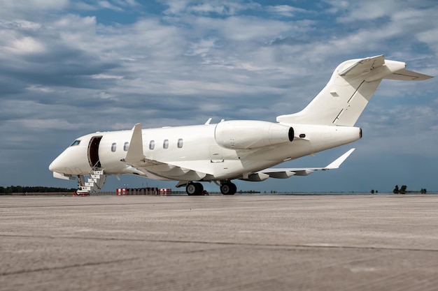 Modern white private jet with an opened gangway door at the airport apron