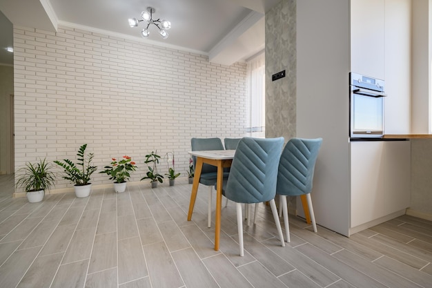 A modern white studio apartment with a dining table and row of green plants