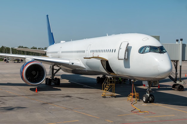 Modern white wide body passenger airliner with open luggage compartment at the airport apron