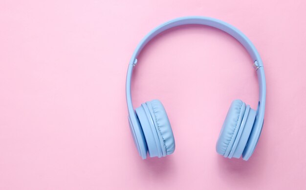 Modern wireless blue headphones on a pink pastel background