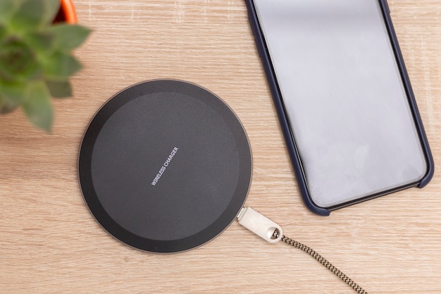 Modern wireless charger for devices, phones and electronics. Smart phone charger on a table, with inscription Wireless charger on the top.