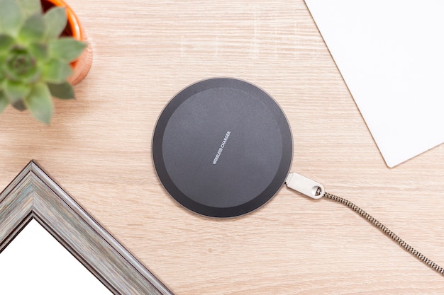 Modern wireless charger for devices, phones and electronics. Smartphone charger on a table, with inscription Wireless charger on the top.