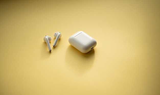 modern wireless earphones on a pastel yellow background