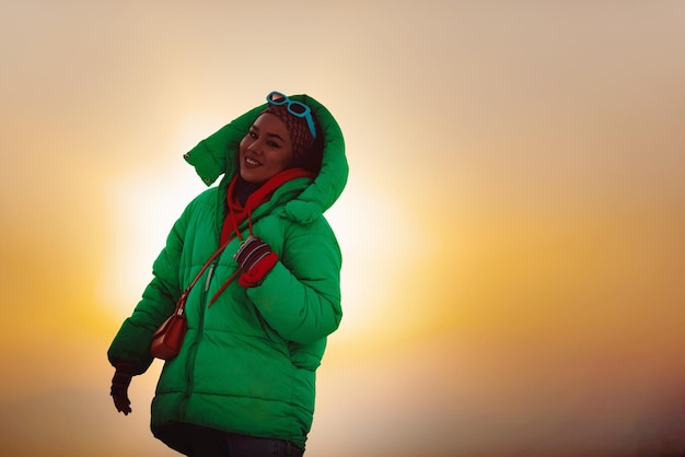 Modern woman in hijab with green jacket posing outdoor