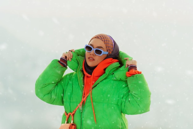 Modern woman in hijab with green jacket posing on a winter day