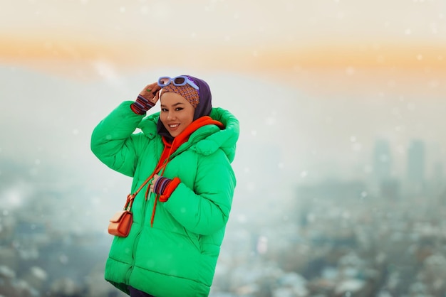 Modern woman in hijab with green jacket posing on a winter day