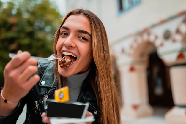 A modern woman sits in the park on a break from college and eats fresh poffertjes