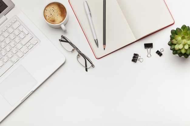 Modern workplace with laptop, notebook, pen and cup of coffee