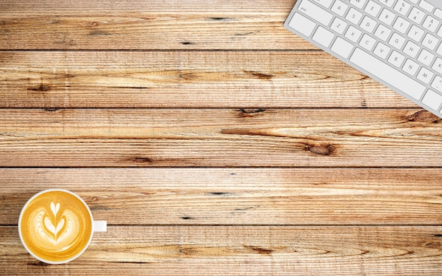 Modern workspace with coffee cup, notebook and keyboard on wood