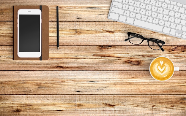 Modern workspace with coffee cup, paper, notebook, tablet or smartphone and keyboard on wood