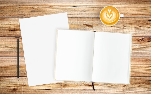 Modern workspace with coffee cup, paper and notebook on wood