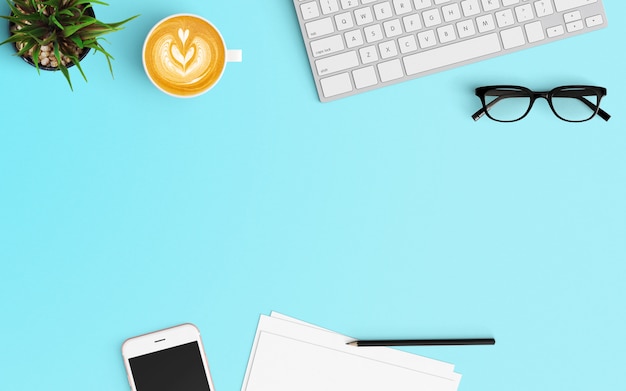 Modern workspace with coffee cup, smartphone, tree, blank papers, keyboard and smartphone on Blue color