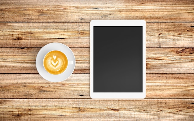 Modern workspace with coffee cup and tablet copy space on wood background. 