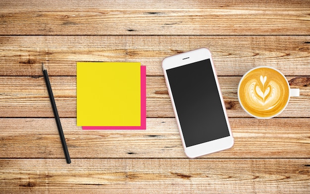 Modern workspace with coffee cup and tablet or smartphone on wood