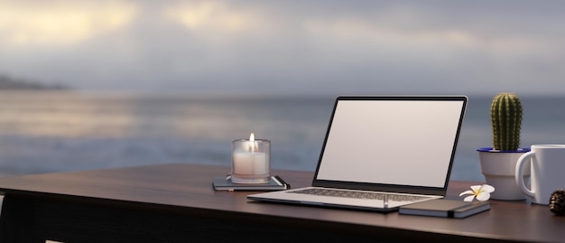 Modern workspace with laptop mockup on table against blurred sea and sky view