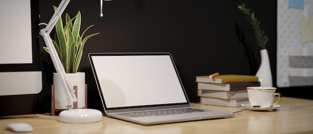 Modern workspace with portable laptop and decors on wood table against the black wall