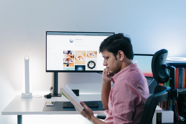 modern young handsome man in casual outfit sitting at table working on laptop