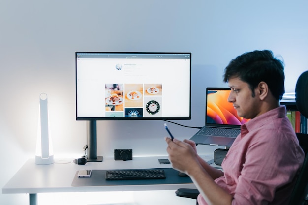 modern young handsome man in casual outfit sitting at table working on laptop