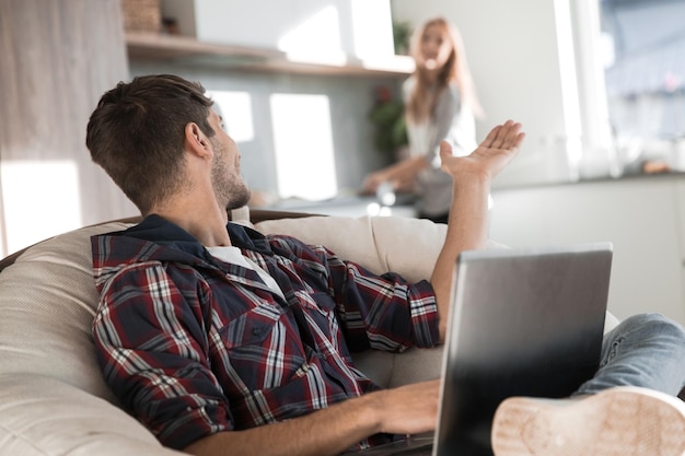 Modern young man with laptop sitting in his kitchen