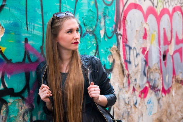 Modern young woman next to graffiti wall