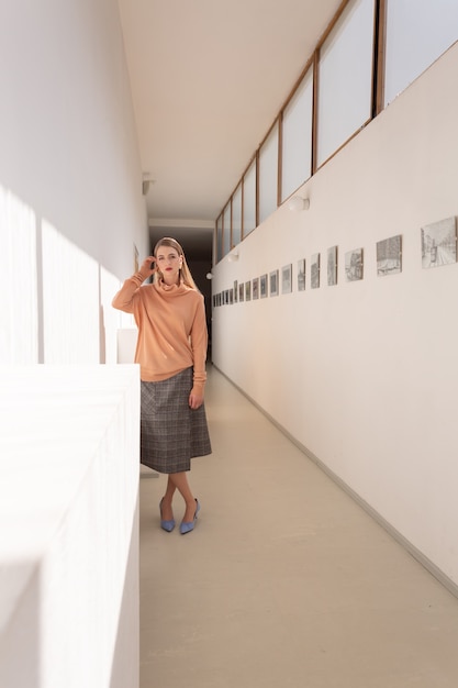 Modest young woman in casual dress posing in the white hall