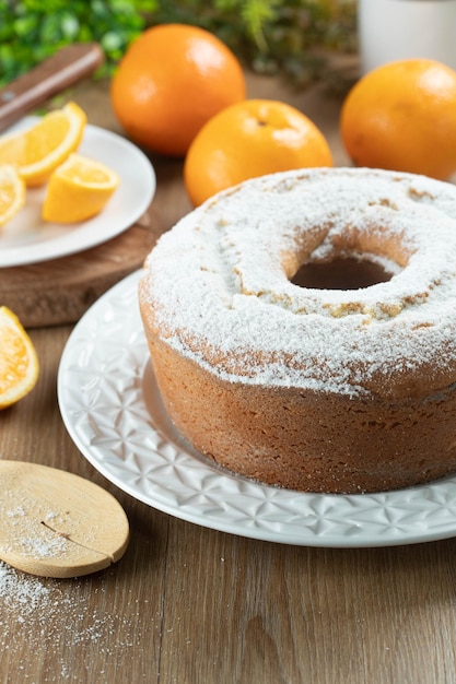 Moist orange fruit cake on plate with orange slices on wooden table Delicious breakfast traditional English tea time Orange cake recipe